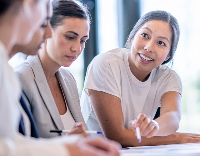 Eine Gruppe von Frauen sitzt zusammen und bespricht Dokumente. (Foto)