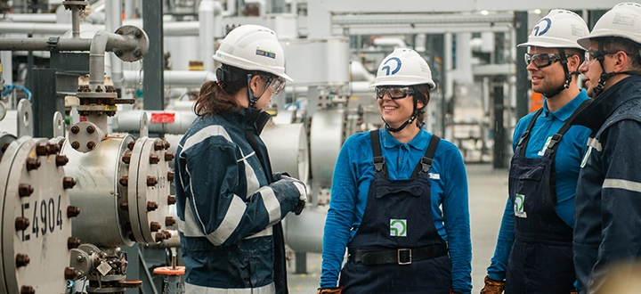 Two OMV employees wearing safety helments standing in a factory (photo)