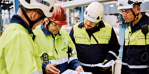 Four Borealis employees in safety gear looking at a clipboard (photo)